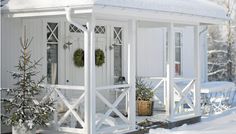 a white house with snow on the ground and potted plants in front of it