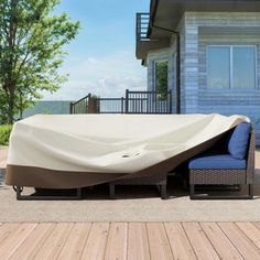 an outdoor couch with a cover on it in front of a house that is next to a deck