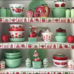 the shelves are filled with dishes and other kitchenware, such as strawberry - themed bowls