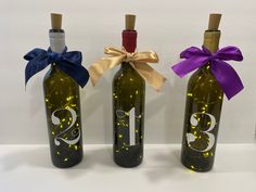 three wine bottles with ribbons tied around them and the number thirteen on each one bottle