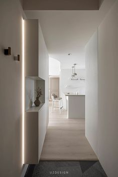 an empty hallway leading to a kitchen and dining room with lights on the side of it