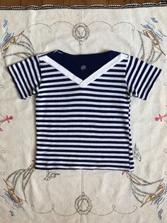 "RARE 1950s striped t-shirt with an embroidered boat wheel in navy blue and white stripes. I do think this is a juniors t-shirt but will fit a small adult.  Label: none  Measurements: { xxsmall } Pit to Pit: 14.5\"-18.5\" Length: 17\" Sleeve Length: 5.5\" Armhole is about 13\" around approx.  Condition: fabric is worn as shown in photos but still totally wearable and presents well. washed and ready to wear - sold as found. Shop more: www.trunkofdresses.com" Navy Marine Style Cotton Top, Navy Cotton Marine Style Tops, Summer Marine Style Cotton Tops, Marine Style Cotton Tops For Summer, Blue Cotton Tops For Boating, Nautical Style Cotton Top In Sail Color, Retro Navy Tops For Summer, Sail Color Cotton Short Sleeve Tops, Nautical Style Sail Color Short Sleeve Tops