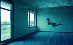 a woman floating in an empty room under water