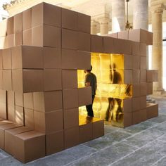 a man is standing in the doorway of a building made out of cardboard boxes