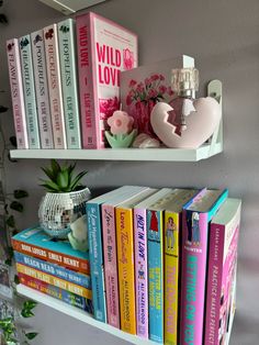 two white shelves filled with books on top of each other next to a potted plant