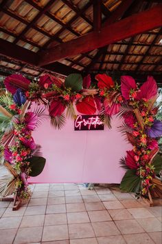 an outdoor area with pink walls and flowers on the wall, surrounded by palm leaves