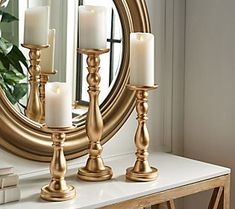 three candles are on a table in front of a mirror with a large gold frame