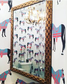 a bathroom with horse wallpaper on the walls and a toilet in the middle, next to a mirror