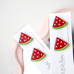 two watermelon shaped magnets sitting on top of a white card next to each other