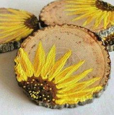 three sunflowers are sitting on wood slices that have been painted yellow and brown