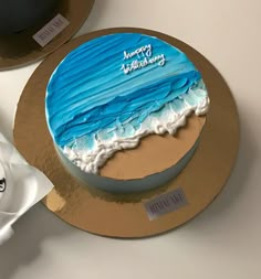 a blue and white birthday cake sitting on top of a table next to a cup