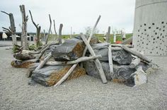 a pile of rocks and sticks sitting on top of a gravel ground next to a cement wall