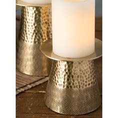 two gold - plated candles are sitting on top of each other, one with a white candle in it