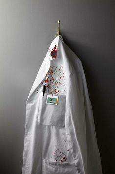 a white shirt with blood on it hanging from a hook