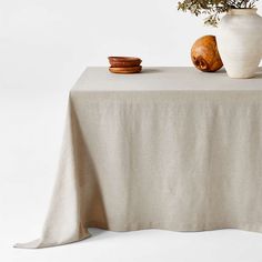 a white vase sitting on top of a table next to a wooden bowl filled with flowers