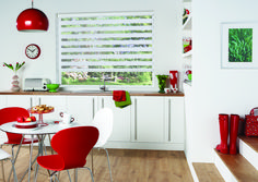 a white kitchen with red chairs and a round table in front of a window that has blinds on it