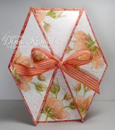 an origami umbrella with orange flowers and a bow on the top is decorated with gingham ribbon