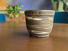 a wooden table topped with a brown and white cup on top of it's side