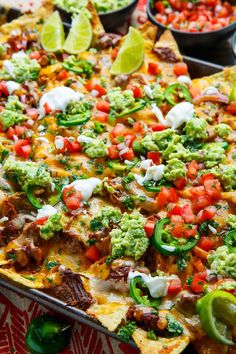 a tray filled with nachos covered in cheese and toppings next to salsa