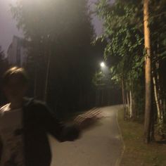 a man riding a skateboard on top of a cement ramp at night with trees in the background