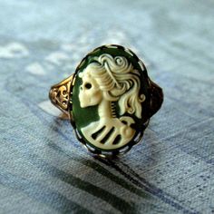 18x13mm green and cream acrylic skeleton lady cameo.On an antiqued brass cigar band style ring. Easy to adjust to most sizes.Let me know if you'd rather this on an antiqued silver plated ring band. See other color options in the last photo. Black Cameo Ring As Gift, Victorian Cameo Rings As Gift, Vintage Gold Cameo Ring, Vintage Adjustable Cameo Rings, Cameo Ring Gem, Antique Silver Rings, Cameo Ring, Steampunk Accessories, Cameo Jewelry