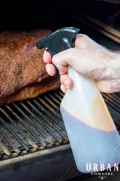 a person is holding a bottle with something in it while cooking food on the grill