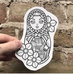 a hand holding up a sticker that has an image of a woman with flowers on it