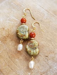 These Aqua Shell and Freshwater Pearl earrings are made of exquisitely detailed Bohemian glass from the Czech Republic.The glass beads are in the shape of an Ammonite shell. We add a tiny pearl dangle and an orange agate accent bead. Antiqued gold spacers bring together this fresh beachy look.The earrings measure approximately 2" in length.Gold plated stainless steel hooks. Lightweight and comfortable. Also available in other colors. © All artwork, jewelry designs and digital images are the prop Bead Styles, Ammonite Shell, Orange Agate, Freshwater Pearl Earrings, Freshwater Pearls Earrings, Jewelry Lookbook, Moon Design, Coral Beads, Shell Earrings