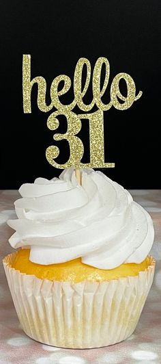 a cupcake with white frosting and a gold hello 31 cake topper