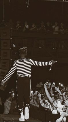 a man standing on top of a stage with his arms outstretched in front of an audience