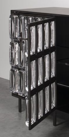 a black cabinet with silver foil covering it's doors and drawers on each side