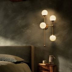 a bed room with a neatly made bed and three lights on the wall above it