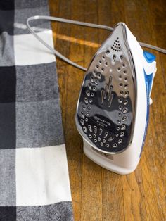 an iron is sitting on the floor next to a plaid tablecloth with a black and white checkered cloth