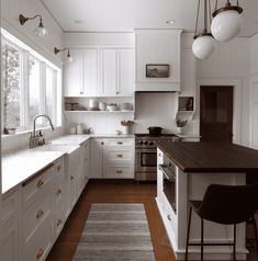 a kitchen with white cabinets and wood floors