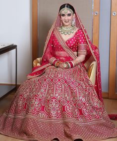 a woman sitting in a chair wearing a red and gold bridal gown