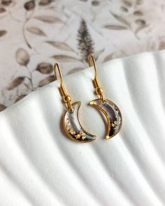 🌙 These stunning moon earrings are the perfect accessory for any celestial jewelry lover. The moons are made of black and transparent resin, with gold flakes inside, which gives them a sleek and modern look. They are set in golden stainless steel bezels, which gives them a luxurious and elegant touch. 🌙 Measuring approximately 1 cm x 1.5 cm (0.4 inches x 0.6 inches) without the hooks, what makes them the perfect size for everyday wear or special occasions. 🌙 Each pair of earrings is handmade Gold And Black Earrings, Black Celestial Earrings For Gift, Black Moon-shaped Earrings For Gift, Black Moon Shaped Earrings For Gift, Dainty Moon Phase Earrings For Gift, Dainty Moon Phase Earrings As Gift, Black Moon Charm Celestial Earrings, Black Celestial Earrings With Moon Charm, Black Moon Shaped Celestial Earrings