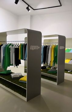 an empty clothing store with clothes hanging on racks and green grass in the flooring