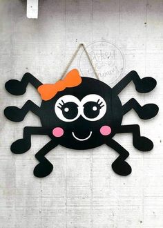 a black and orange spider hanging on a wall with a bow in it's hair