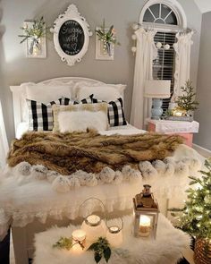 a white bed topped with pillows and blankets next to a christmas tree in a bedroom