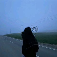 a person riding on the back of a motorcycle down a road in the foggy day