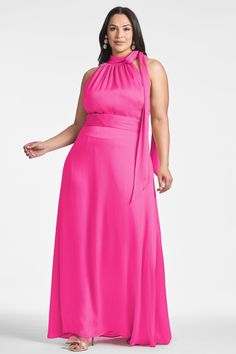 a woman in a bright pink dress poses for the camera with her hands on her hips