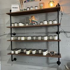 shelves with jars and candles on them against a white brick wall in a store or restaurant