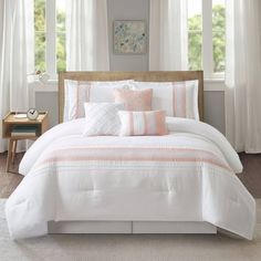 a bed with white sheets and pink pillows