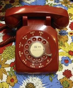 an old red telephone sitting on top of a bed