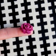 a tiny pink flower sitting on top of a finger