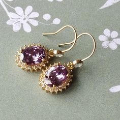 These pretty Regency style earrings comprise of gold filled ear wires which have  white topaz stones. These support oval violet Swarovski crystals surrounded by tiny clear round Swarovski crystals. These earrings would be great for a Regency ball or for any special occasion. Limited edition design. Gold filled ear wires. Length (from top of ear wire to bottom of earring) 3.1cm (1.22 inches). Please note: All photos are taken under natural light. However different computer screens, operating syst Regency Ball, Regency Costume, Topaz Stone, Style Earrings, Jane Austen, White Topaz, Ear Wire, Ear Wires, Beautiful Earrings