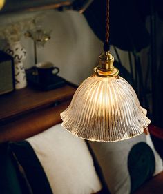 a light hanging from a ceiling in a living room next to pillows and a table