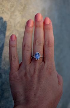 a woman's hand with a ring on it and a blue stone in the middle