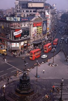 an aerial view of a busy city street with buses, pedestrians and buildings in the background