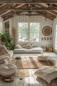 a living room filled with lots of white furniture and pillows on top of wooden flooring